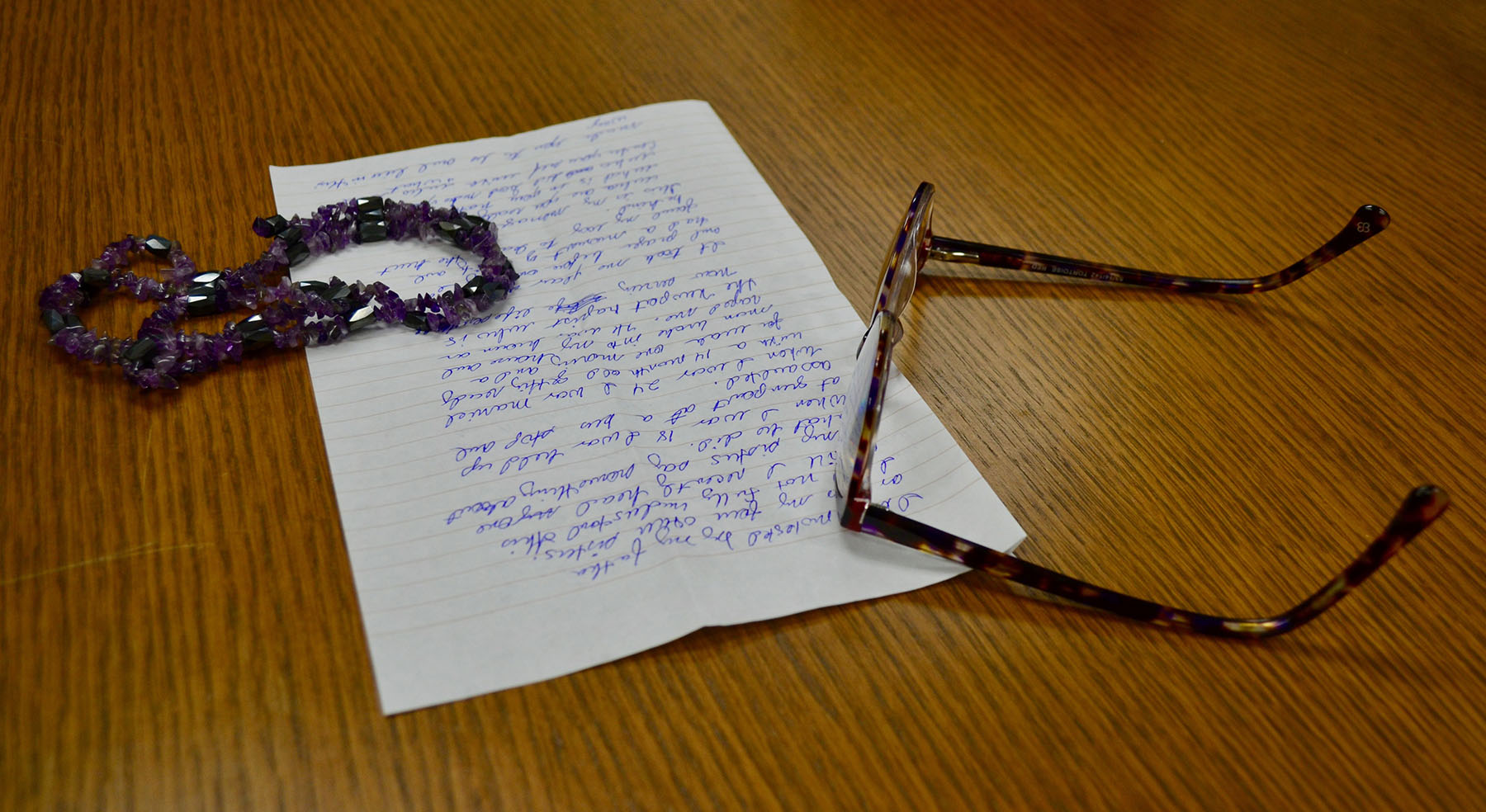 Written notes, glasses and a necklace on a table