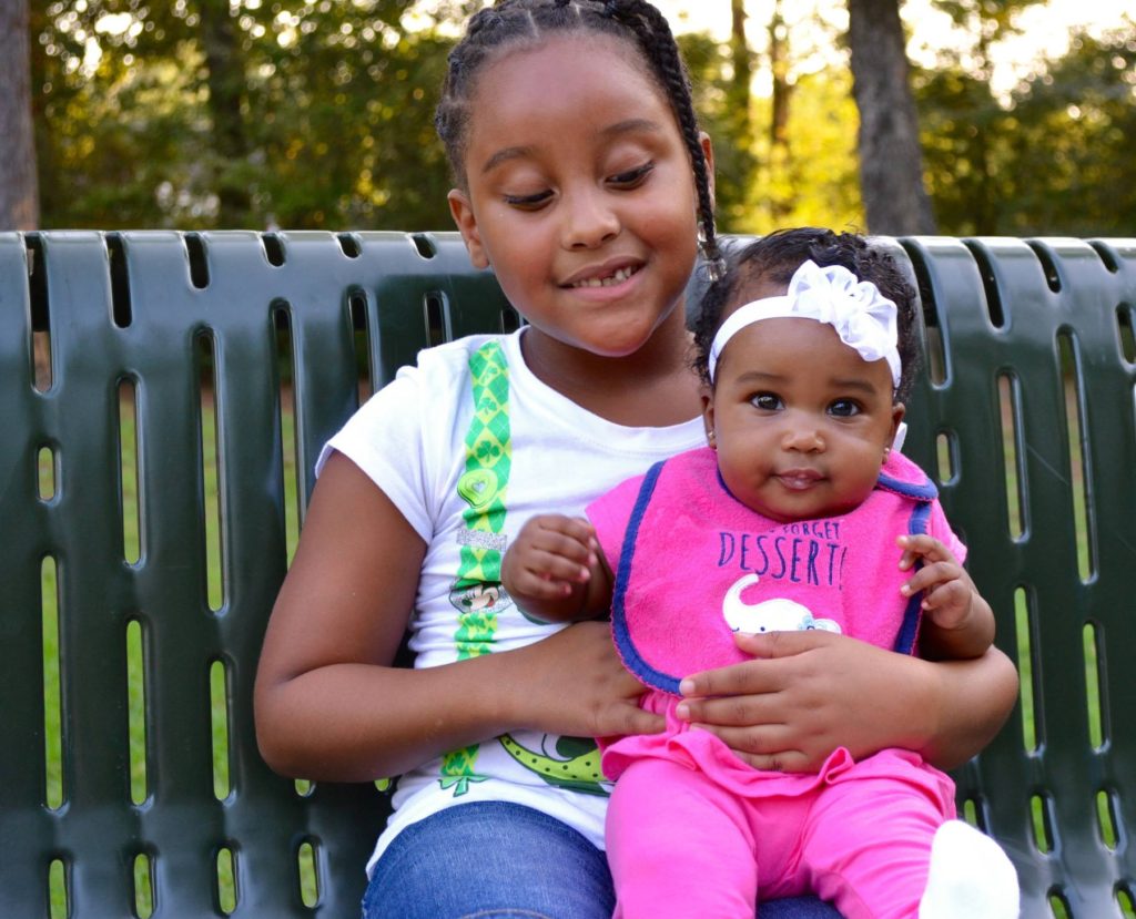 Aldrina and Brianna sit on a park bench