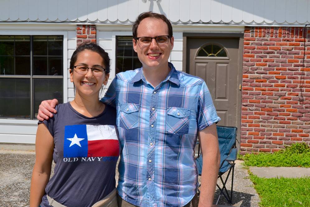 Couple stand in front of their home