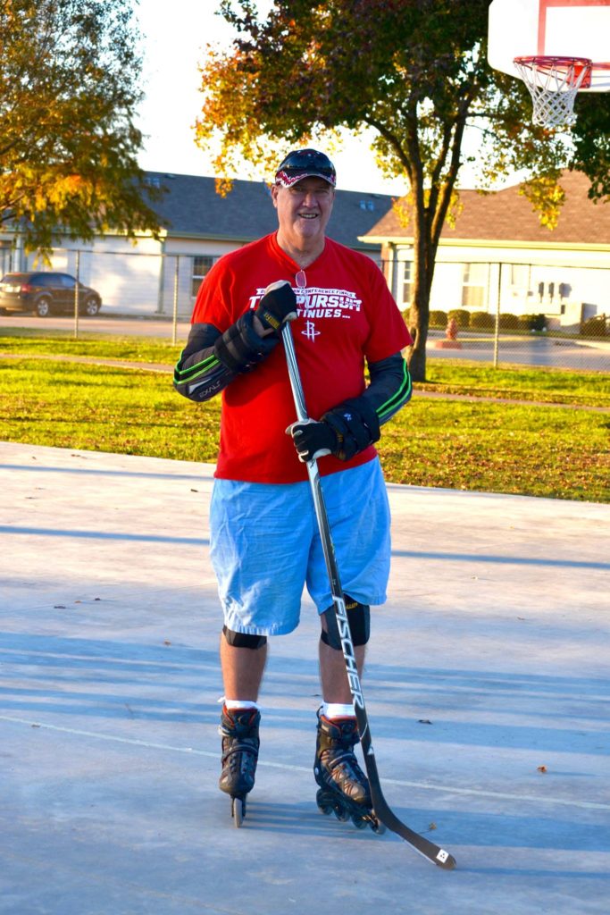 Stephen Lee roller skates holding hockey stick