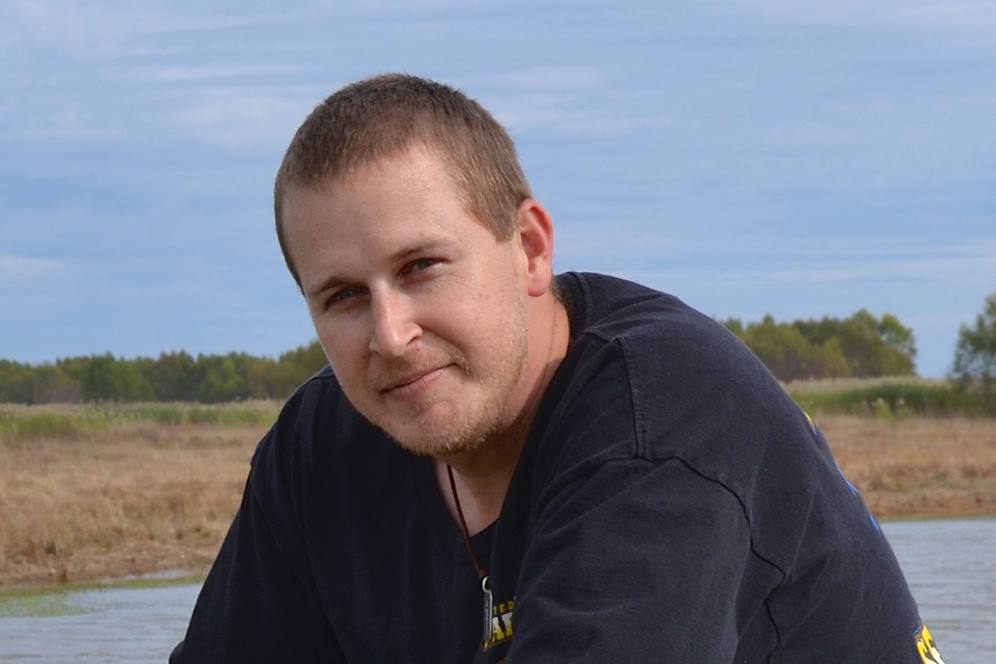 Young man kneels near water