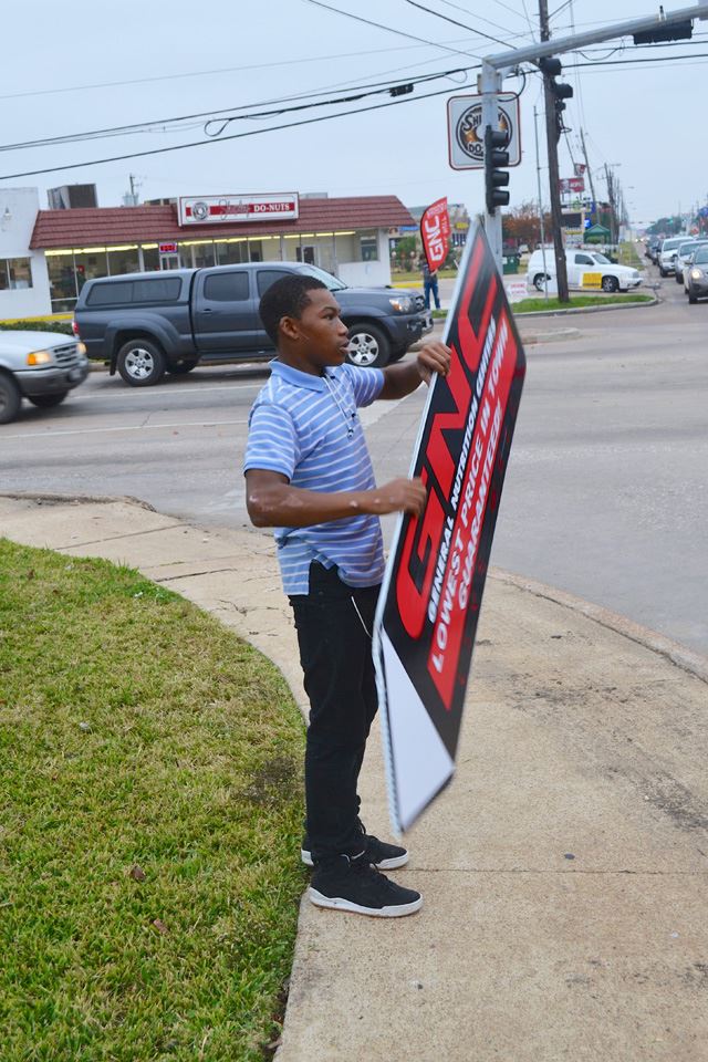 Young man twirls sign on street corner