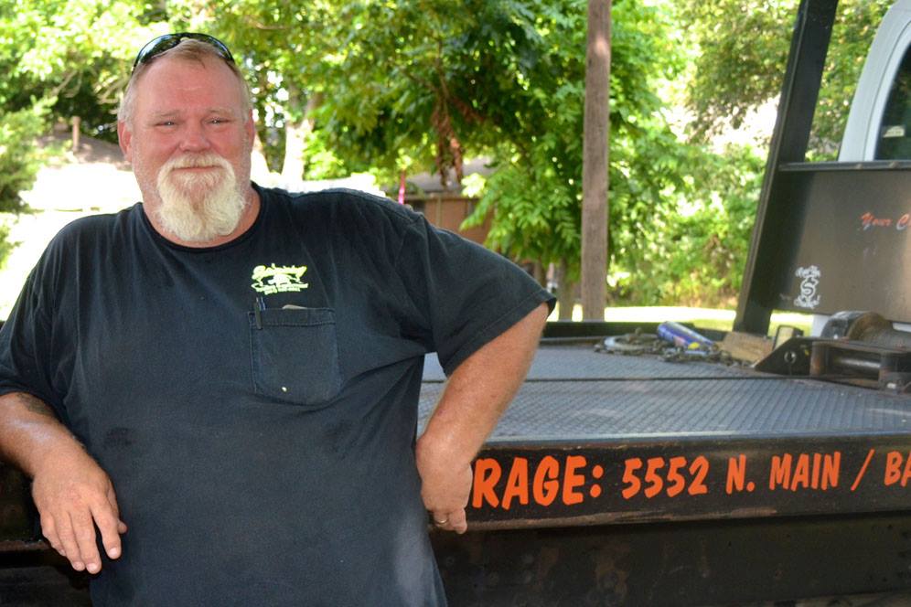 Wrecker driver stands near truck