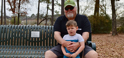 Steve Brown sits on a park bench with his grandson