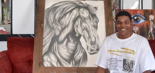 Welton Williams sitting next to his paintings