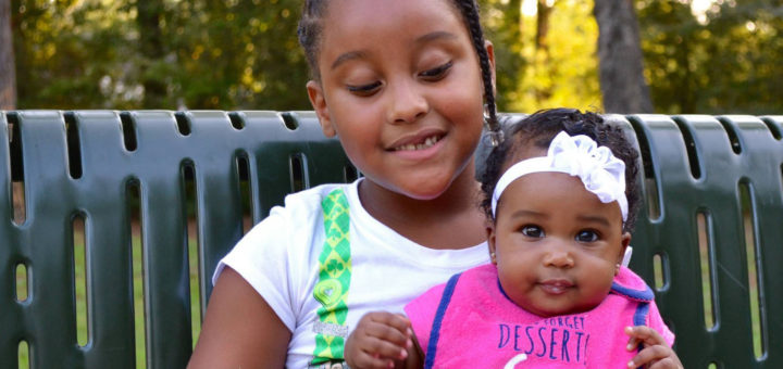 Aldrina and Brianna sit on a park bench