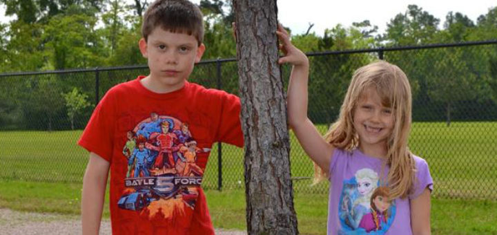 Brother and sister stand near a tree