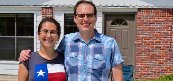 Couple stand in front of their home