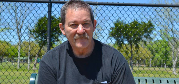 Man sits on bench at dog park