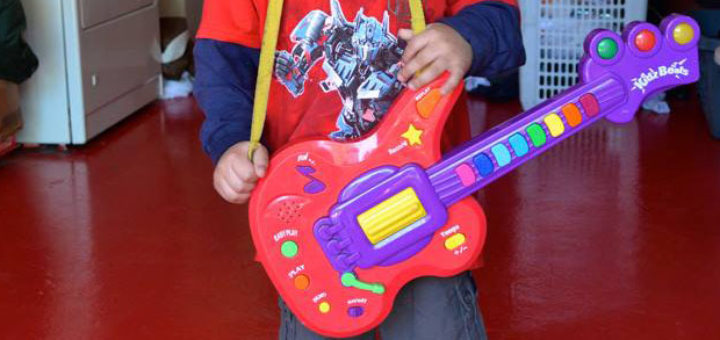 Young boy plays with toy guitar
