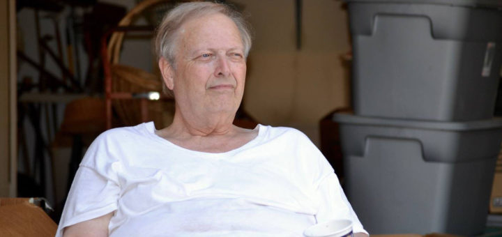 Roy Christina sits in front of his garage