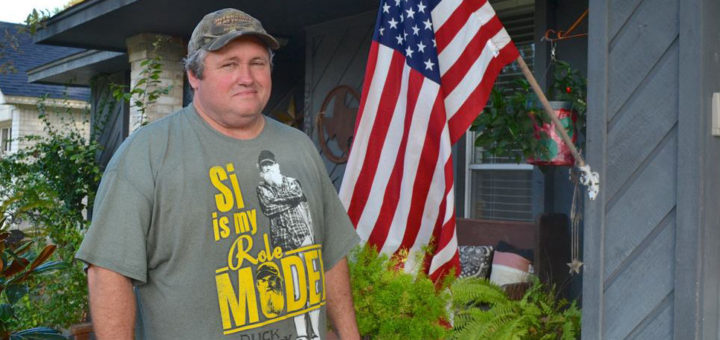 Business owner stands near flag