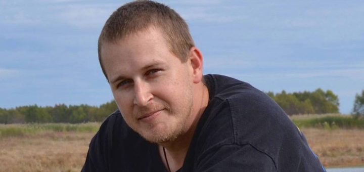 Young man sits near water