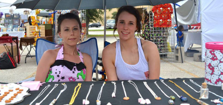 Two young women sitting at table of miniature items