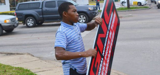Young man twirls sign on street corner
