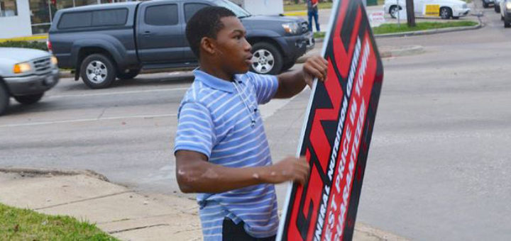 Young man twirls sign on street corner