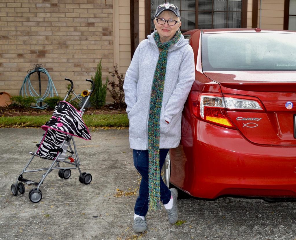 Betty Arabie leans against her car